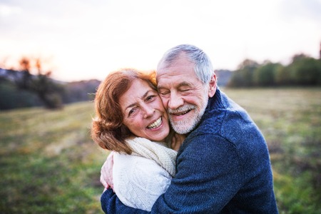 Senior couple hugging in an autumn nature at sunset.