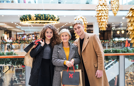 A portrait of grandmother and teenage grandchildren in shopping center at Christmas.の写真素材