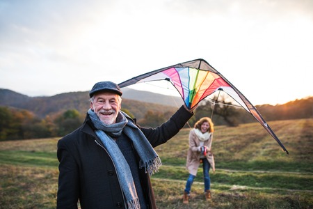 Carefree senior couple flying a kite in an autumn nature at sunset.の写真素材