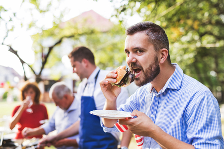 A mature man with family and friends cooking food on a barbecue party.の写真素材