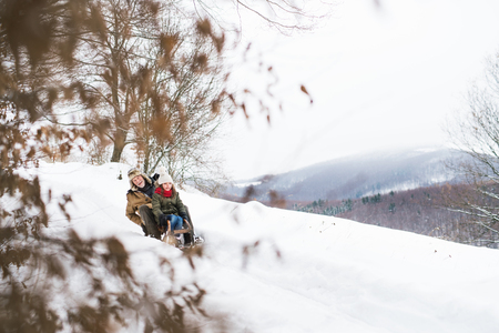 Grandfather and small girl sledging on a winter day.の写真素材
