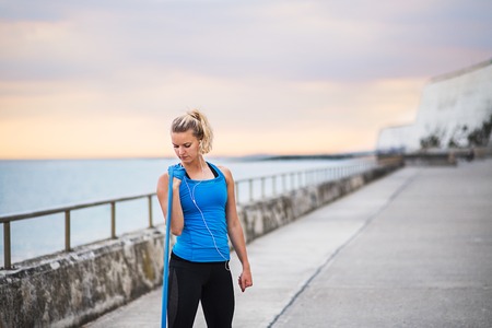 Young sporty woman runner with elastic bands outside on a beach, exercising.の写真素材