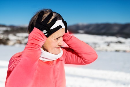 Senior woman runner resting in winter nature.の写真素材