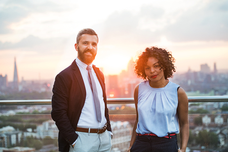 Two businesspeople standing against London rooftop view at sunset.の写真素材