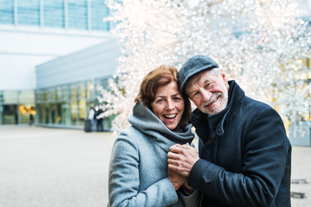 A senior couple standing outdoors in front of shopping center at Christmas time.の写真素材