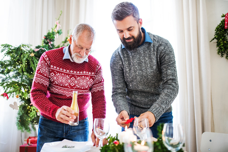 A senior father and adult son setting a table for dinner at Christmas time.の写真素材
