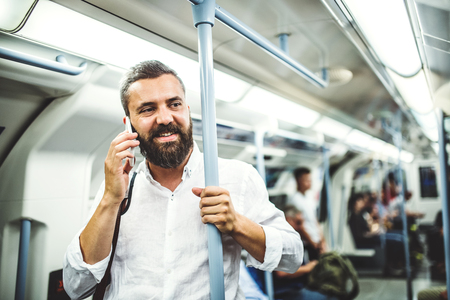 Hipster businessman with smartphone inside the subway in the city, travelling to work.の写真素材