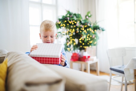 A small boy with opening up a present at home at Christmas time.の写真素材