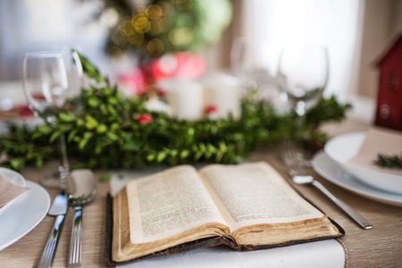 Holy bible book on a table set for a dinner at home at Christmas time.の写真素材
