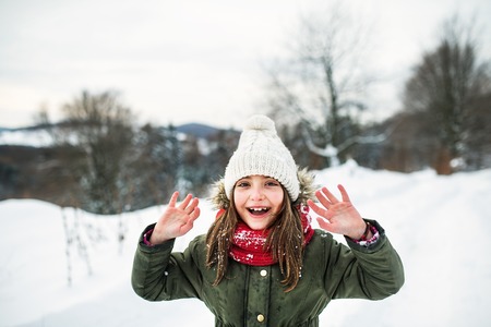 Portrait of a small girl in winter nature, wearing coat, hat and scarf.の写真素材