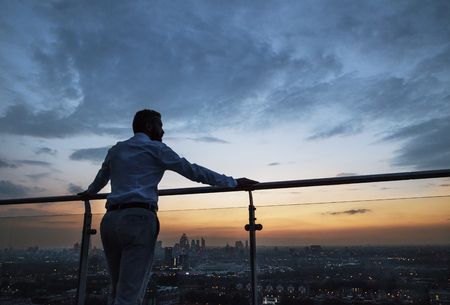 A rear view of businessman standing against London view panorama at dusk.の写真素材