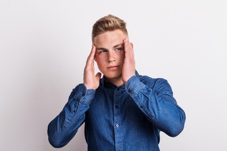 Portrait of a young man in a studio, having headache.の写真素材
