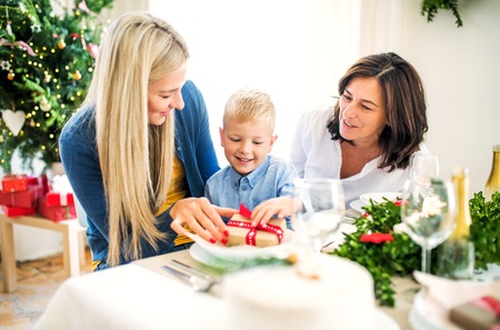 A small boy with present and mother and grandmother at home at Christmas time.の写真素材