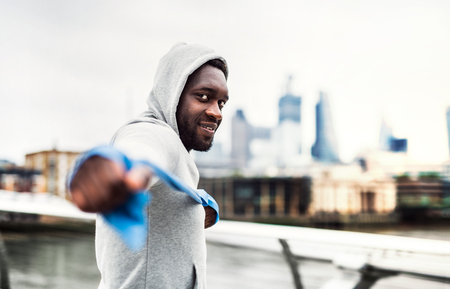 Young black sportsman exercising with elastic rubber bands in London.の写真素材