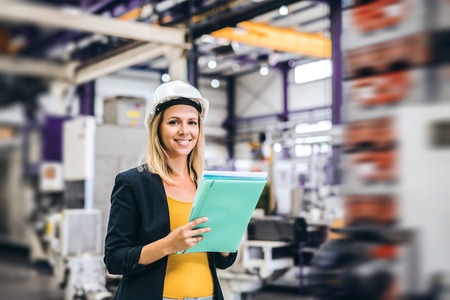 A portrait of an industrial woman engineer in a factory, checking something.の写真素材