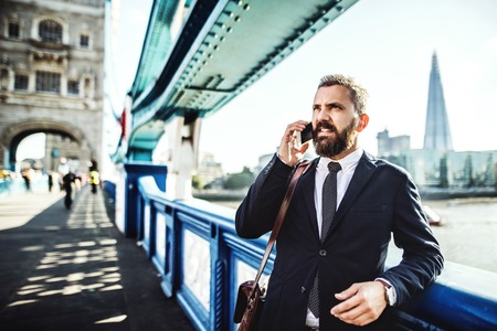 Hipster businessman with smartphone in the London city, making a phone call.の写真素材