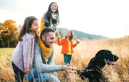 A young family with two small children and a dog on a walk in autumn nature.の写真素材