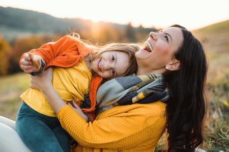 A portrait of young mother with a small daughter in autumn nature at sunset.の写真素材