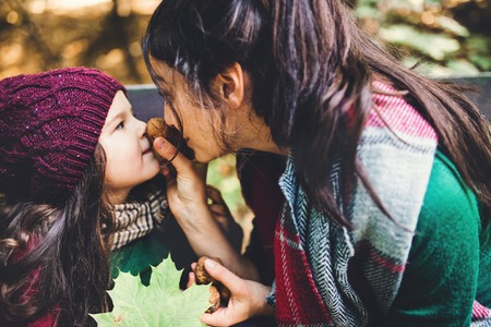 A young mother with a toddler daughter having fun in forest in autumn nature.の写真素材