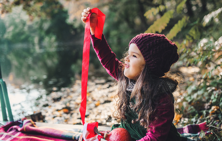 A portrait of a small toddler girl sitting in forest in autumn nature.の写真素材