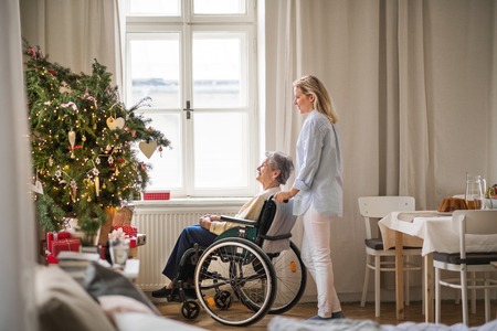 A senior woman in wheelchair with a health visitor at home at Christmas time.の写真素材