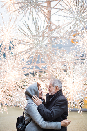 A senior couple standing outdoors in front of shopping center at Christmas time.の写真素材
