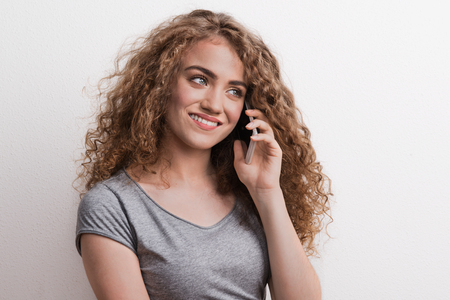 Young beautiful happy woman with smartphone in studio, making a phone call.の写真素材