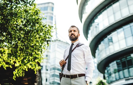 Hipster businessman walking outdoors on the street in London city.