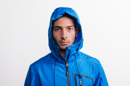 Portrait of a young serious hispanic man with blue anorak in a studio..の写真素材
