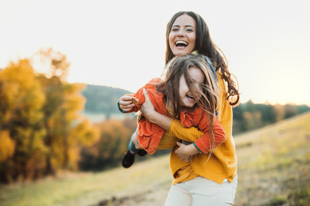 A portrait of young mother with a small daughter in autumn nature at sunset.の写真素材