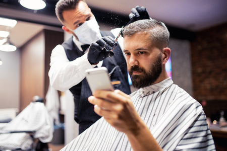 Hipster man client visiting haidresser and hairstylist in barber shop, taking selfie.の写真素材