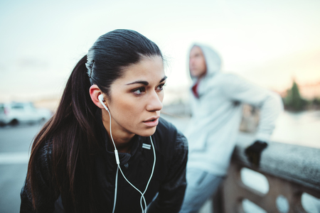 A fit young female runner standing outdoors on the bridge in Prague city.の写真素材