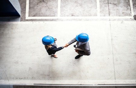 A top view of an industrial man and woman engineer in a factory, shaking hands.の写真素材