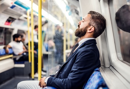 Sleeping hipster businessman inside the subway in the city, travelling to work.の写真素材