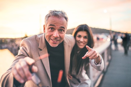 Excited man and woman business partners standing by a river in city at dusk.の写真素材
