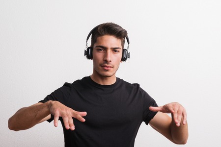 Portrait of a joyful young hispanic man with headphones in a studio. Copy space.の写真素材