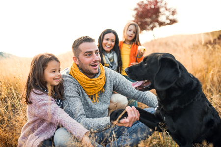 A young family with two small children and a dog on a meadow in autumn nature.の写真素材