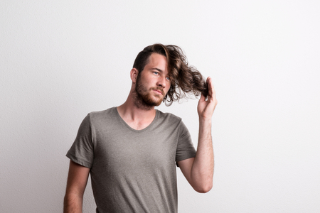 Portrait of a joyful young man with long wavy hair in a studio.