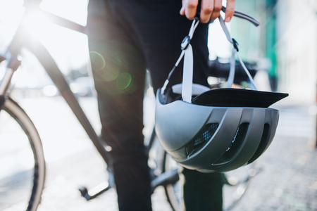 Midsection of man commuter or courier with electric bicycle and helmet in city.の写真素材