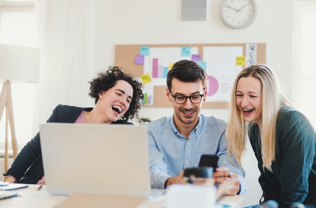 Group of young businesspeople with laptop working together in a modern office.の写真素材