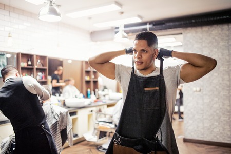 Young hispanic haidresser and hairstylist standing in barber shop.の写真素材