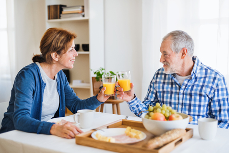 A senior couple sitting at the table at home, having breakfast.の写真素材