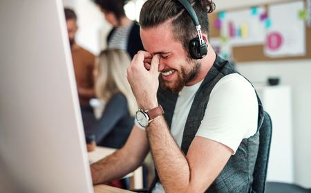 Young businessman with headphones and colleagues in a modern office.の写真素材