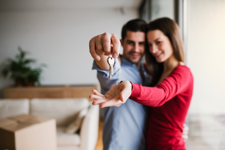 A young couple with a key and cardboard boxes moving in a new home.の写真素材