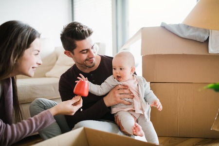 Young couple with a baby and cardboard boxes moving in a new home.の写真素材