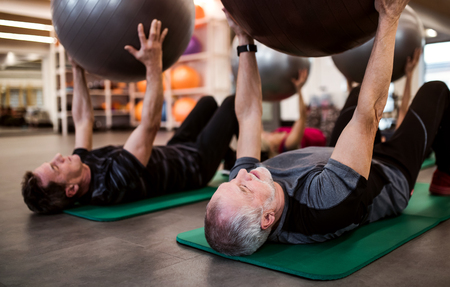 A group of cheerful seniors in gym doing exercise with fit balls.の写真素材