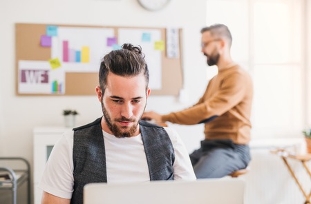Two young male businesspeople with computer working in a modern office.の写真素材