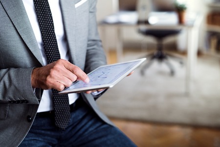 A midsection of businessman sitting in an office, using tablet. Copy space.の写真素材