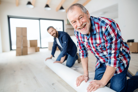A senior man helping his son with furnishing new house, a new home concept.の写真素材