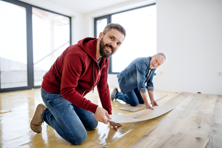 A mature man with his senior father laying vinyl flooring, a new home concept.の写真素材